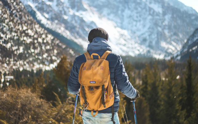 Hiker with a backpack walking along a snowy mountain trail